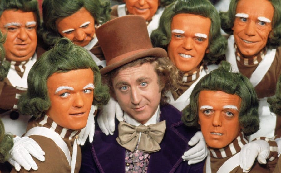 Gene Wilder as Willy Wonka surrounded by Oompa Loompas 