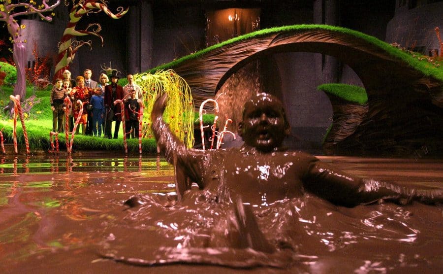 Augustus covered in chocolate struggling to swim in the chocolate river 