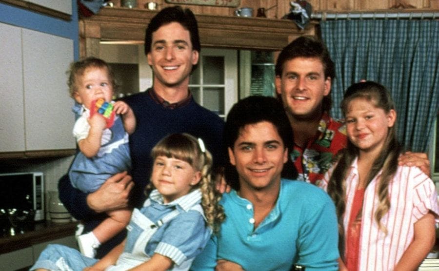 Danny, Joey, and Jesse with the DJ, Stephanie, and Michelle posing in the kitchen in a shot for Full House 