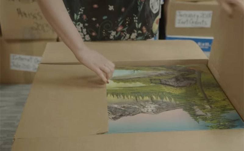 Unpacking a box filled with Bob Ross paintings. 