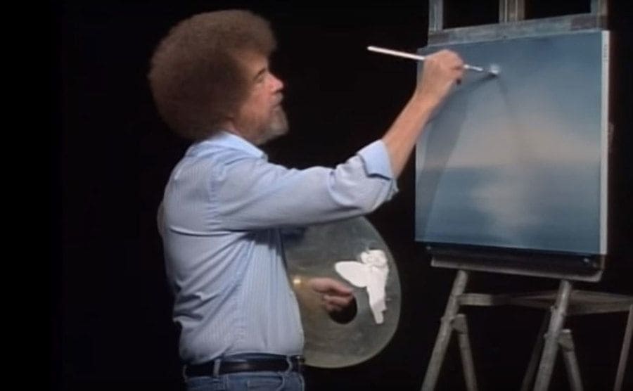 Bob Ross is painting while on set. 