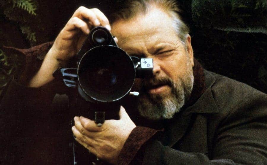 Orson Welles behind the lense of a film camera.
