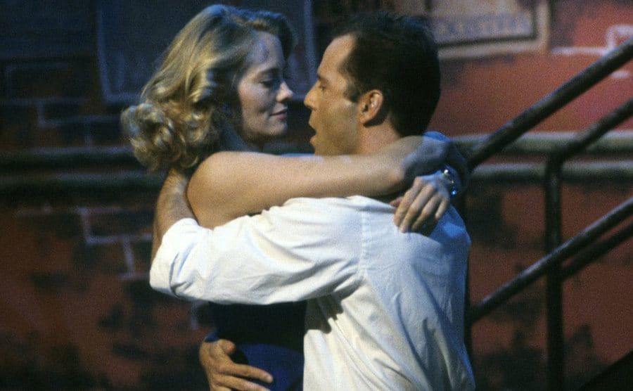 Bruce Willis and Cybill Shepherd are dancing close together. 