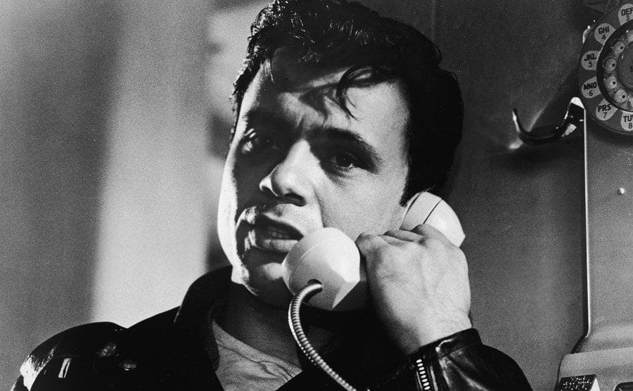 American actor Robert Blake talks on a pay telephone in a still from the film, 'In Cold Blood,'