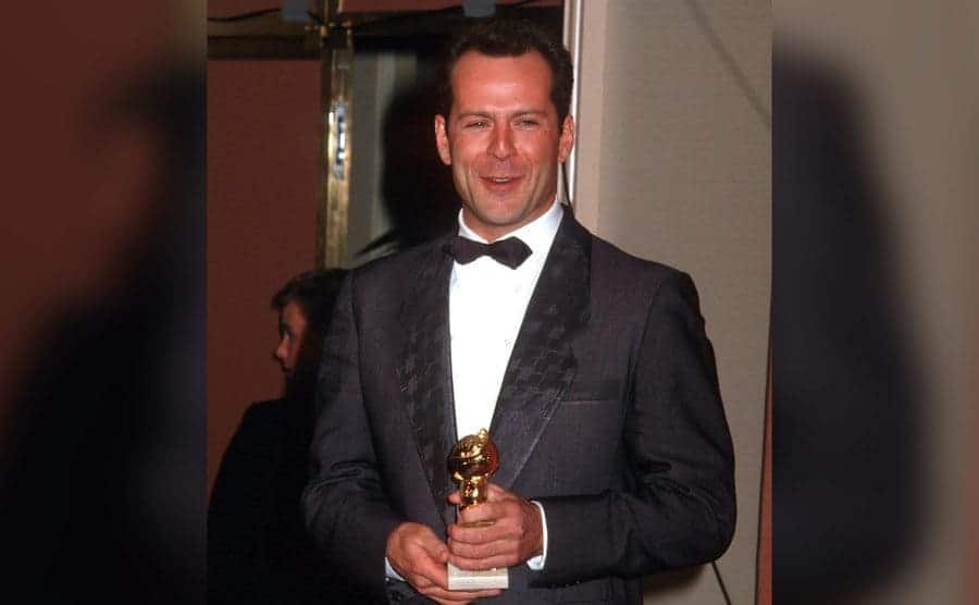 Bruce Willis is holding his Golden Globe. 