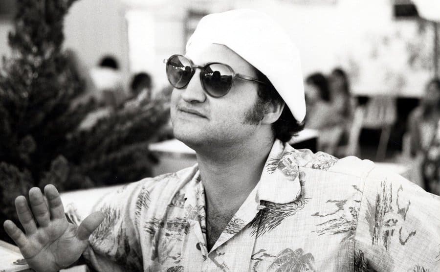 John Belushi in a Hawaiian shirt, sunglasses, and a hat 