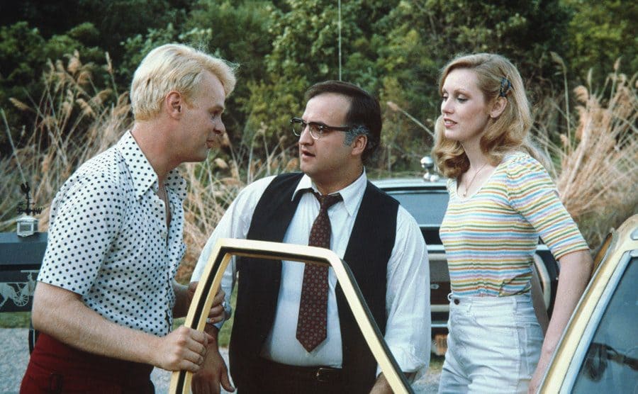 John Belush standing by a car with Dan Aykroyd and Cathy Moriarty in the film Neighbors 