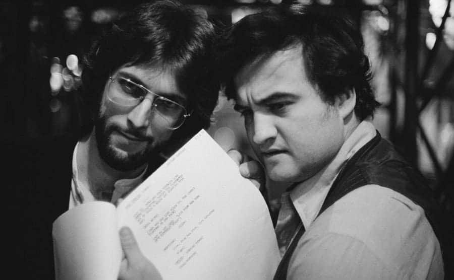 Stephen Bishop and John Belushi posing for the camera with a script in hand
