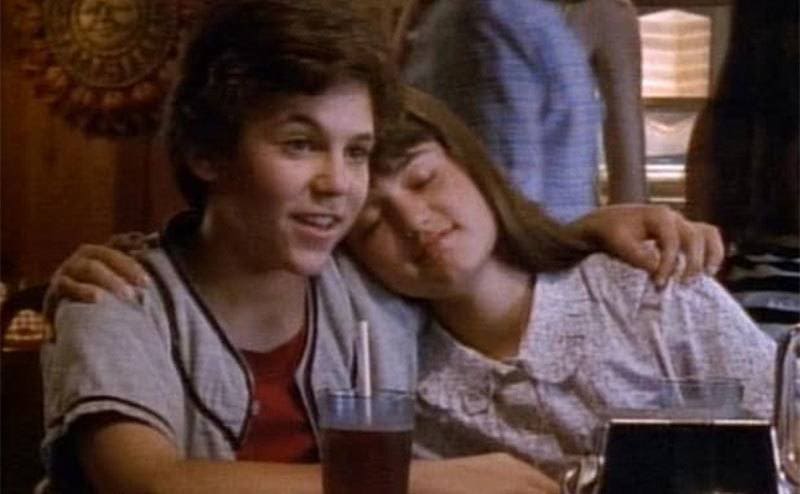 Winnie rests her head on Kevin’s shoulder in a scene from The Wonder Years. 