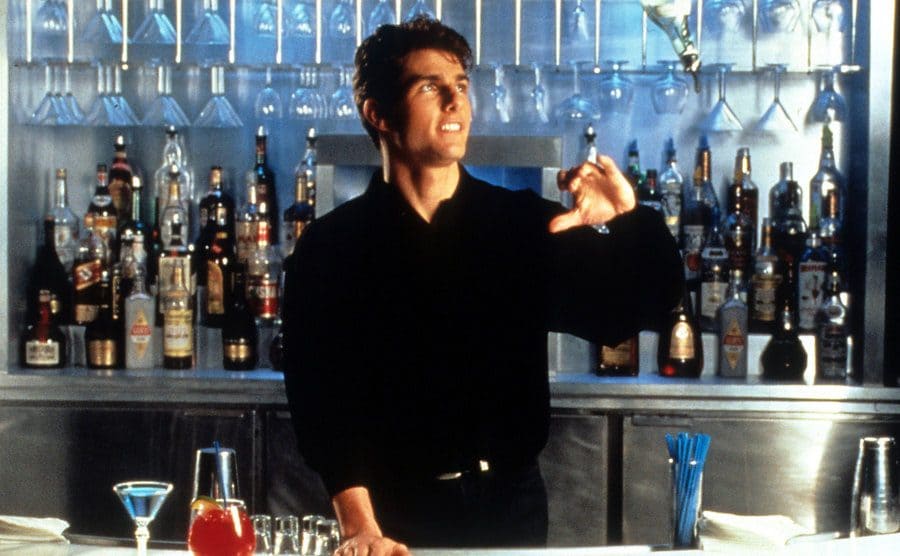 Movie still of Tom Cruise behind the bar flipping a bottle.