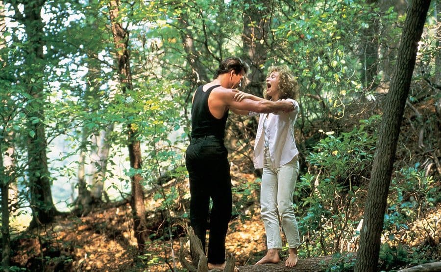 Patrick and Jennifer are practicing moves on a tree trunk in the forest.