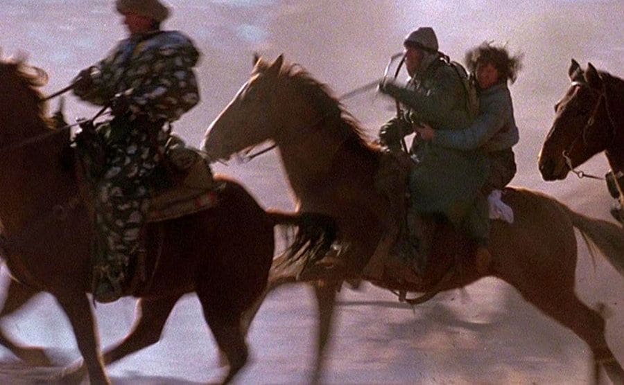 Soldiers riding horses at a very high speed in a movie still from Red Dawn 1984. 