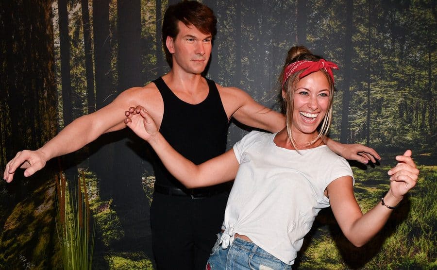 Female fan posing next to Patrick Swayze wax statue at the Dirty dancing area at Madame Tussauds Berlin.