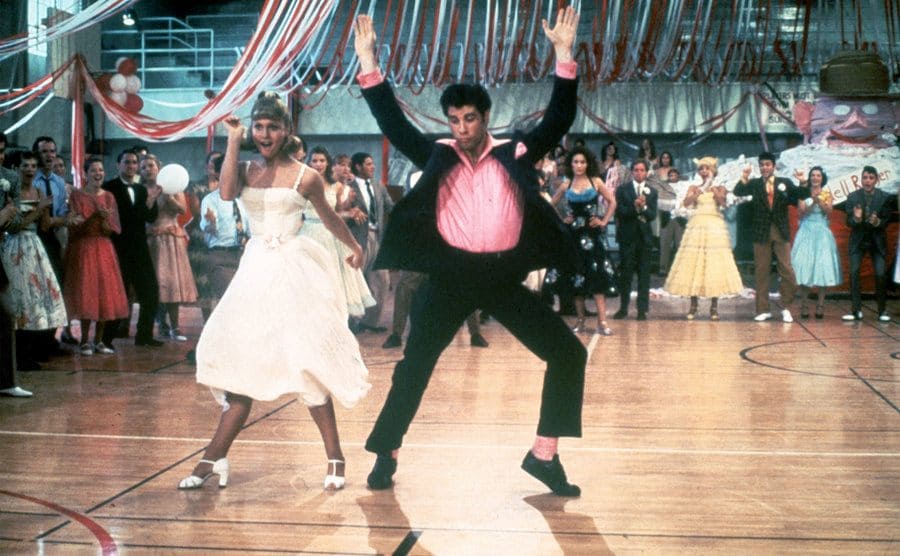Olivia Newton-John and John Travolta dance in a crowded high school gym in a still from the film 'Grease.’ 