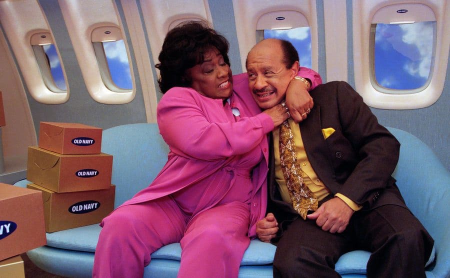 Isabel Sanford is getting into character by grabbing Sherman Hemsley's neck during a break from taping a commercial.
