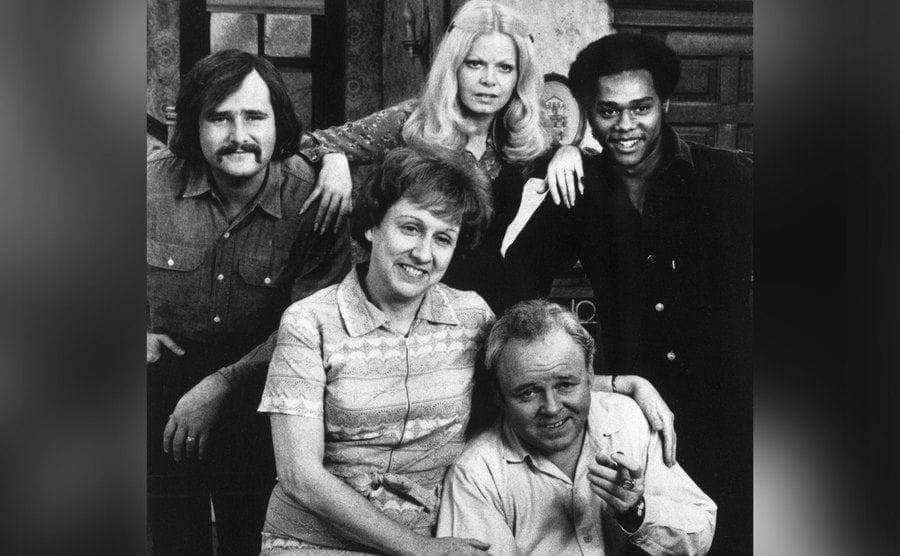 All in the Family cast posing sitting next to each other.