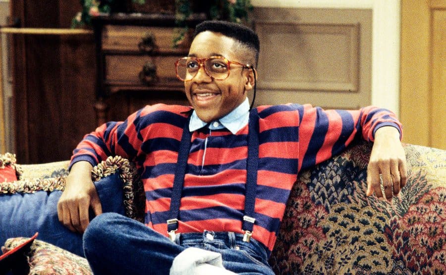 Jaleel White, as Steve Urkel, is sitting on the couch on the set of ‘Family Matters’ 