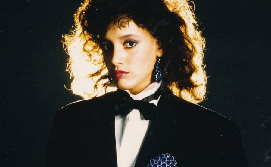 Jennifer Beals is wearing a suit and chunky earrings in a Flashdance publicity shot.