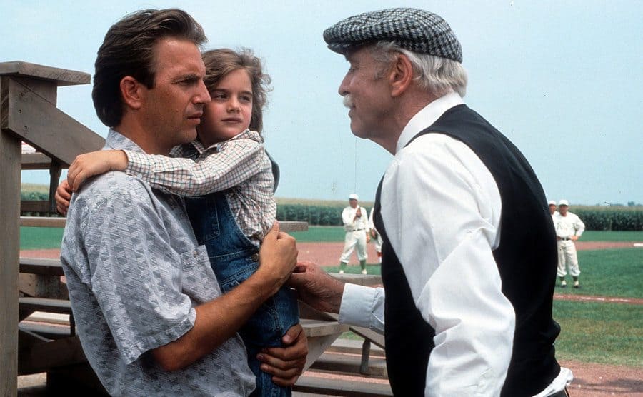 Kevin Costner is holding Gaby Hoffmann in a scene from the film 'Field Of Dreams', 1989.