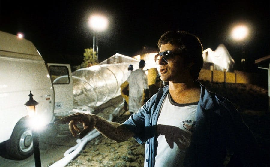 Steven Spielberg is standing beside the structure placed over the house on the set. 