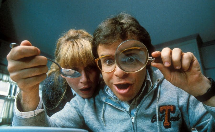 Rick Moranis and Marcia Strassman's baffled expression as they look through a magnifying glass.