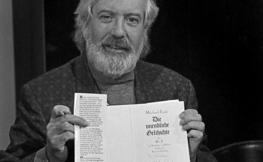 A portrait of Michael Ende holding the book. 