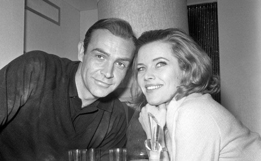 Honor Blackman and Sean Connery leaning towards each other.