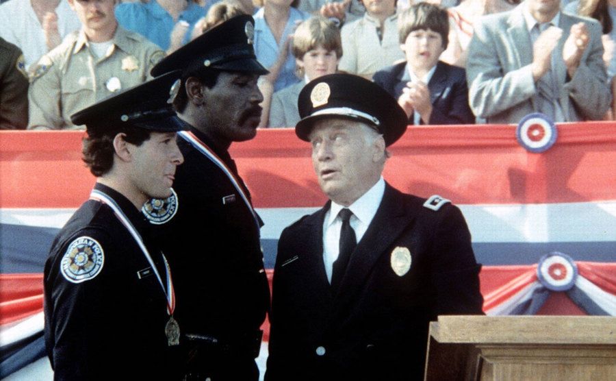 Steve Guttenberg, Bubba Smith and George Gaynes standing next to a podium. 