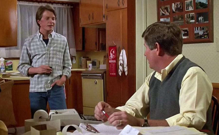 Michael J. Fox and his onscreen dad, James Hampton, talking in the kitchen.
