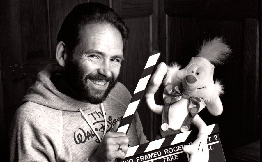 Gary K. Wolf poses with a Roger Rabbit doll and a clapper on set. 