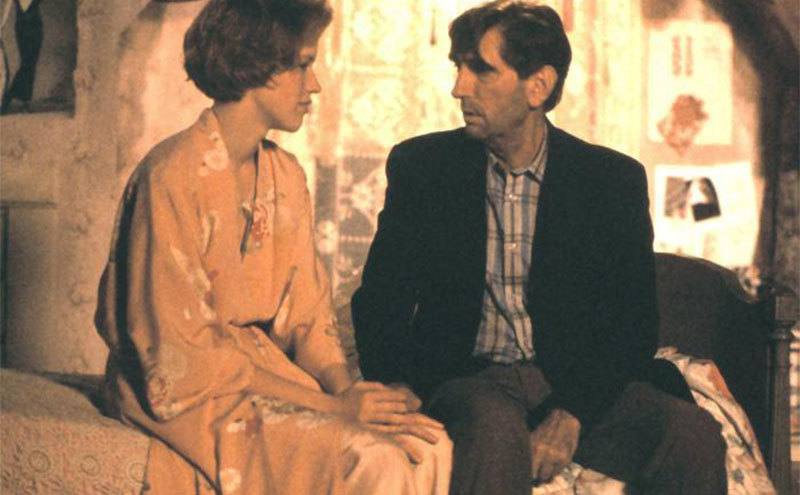 Harry Dean Stanton and Molly Ringwald sit on a bed in a scene from Pretty in Pink. 