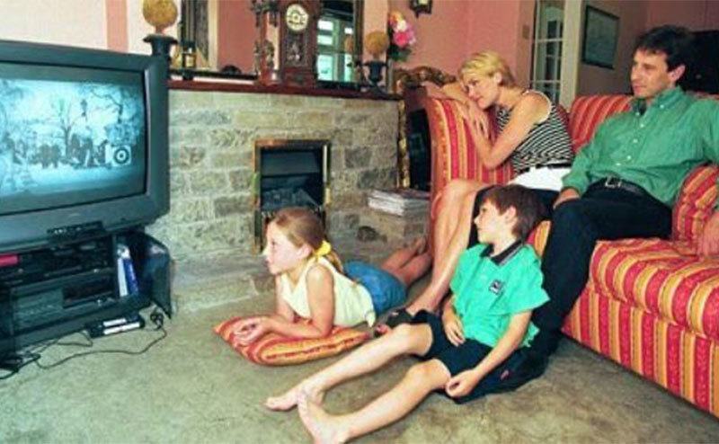 A family sits in the living room watching TV. 