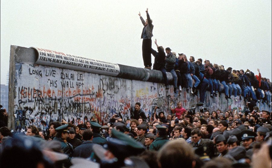 A man celebrates on the Berlin wall after it opens. 