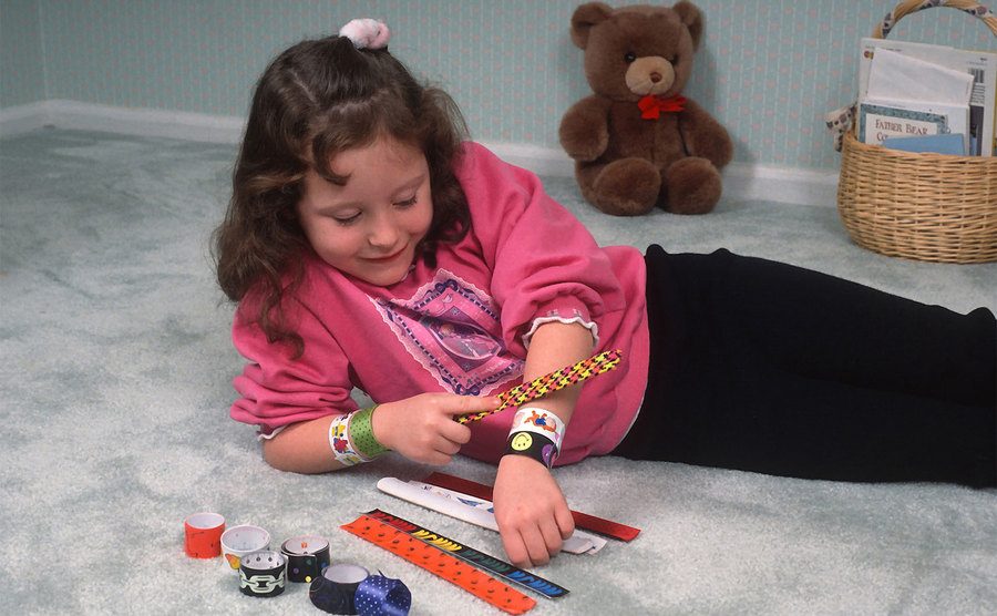 A little girl plays with her slap wrap bracelets. 