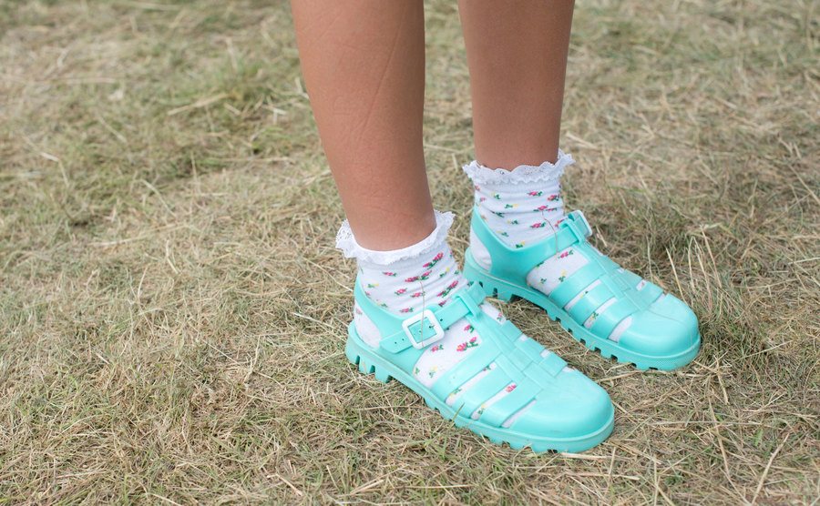 A girl wears jelly shoes with frilly socks. 