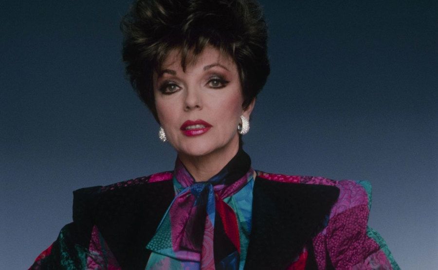 Joan Collins poses as Alexis Carrington Colby in a studio portrait. 
