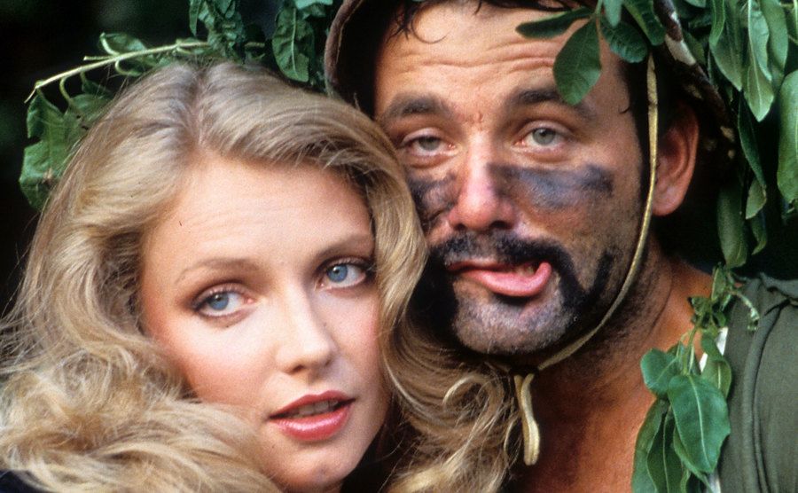 Cindy Morgan and Bill Murray nestled behind a tree in a scene from the film.