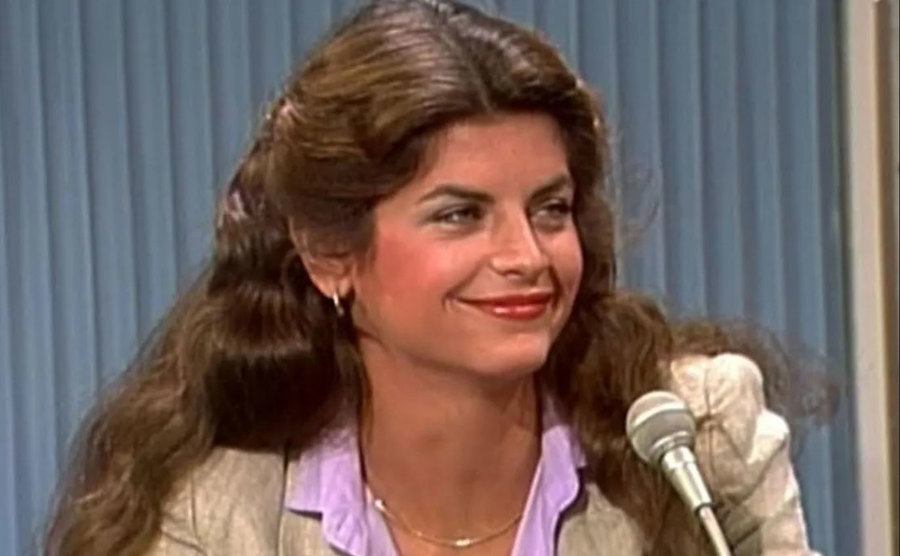 A photo of Kirstie Alley speaking at a microphone.