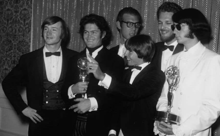 A portrait of The Monkees holding their two Emmy Awards.