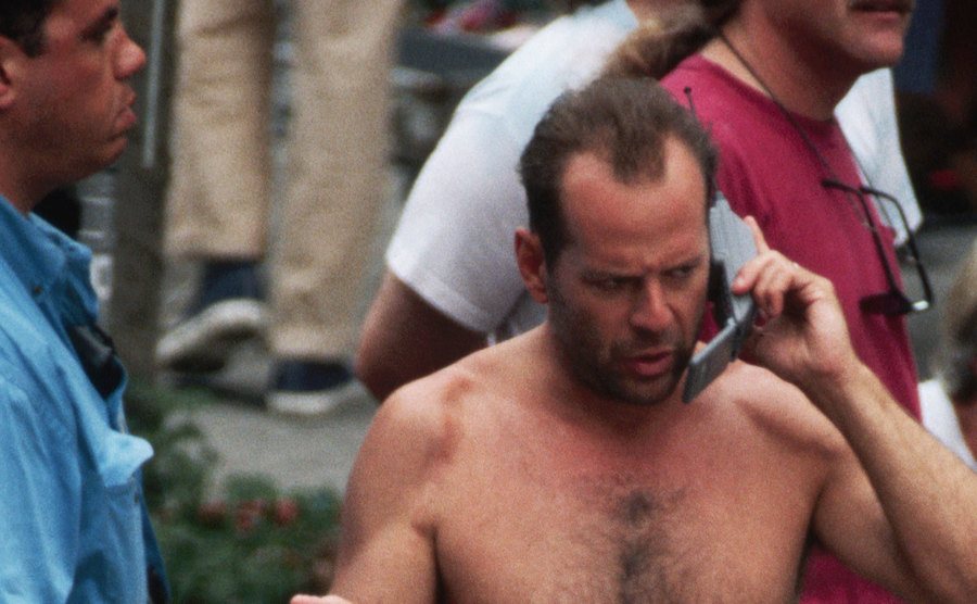 A photo of Bruce Willis speaking on the phone on the set of Die Hard.
