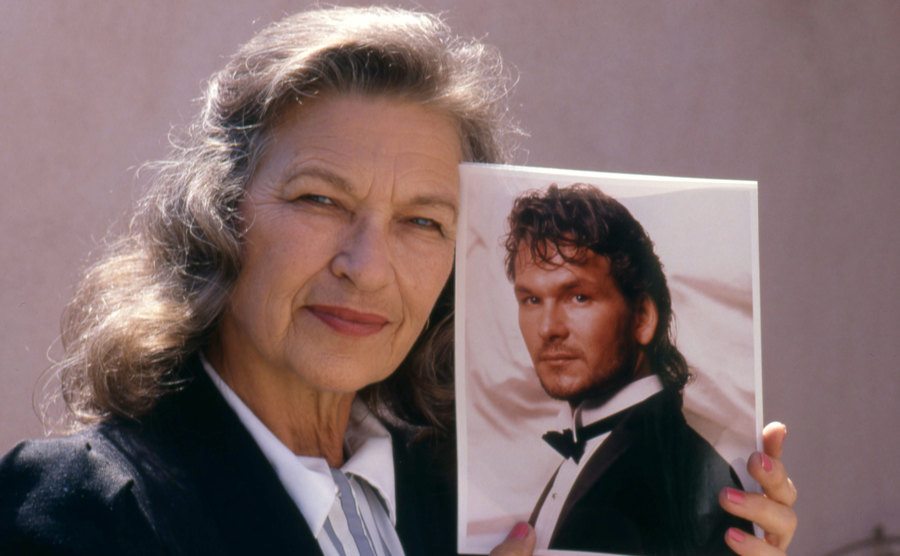 Patrick Swayze's mom poses, holding a picture of her son.