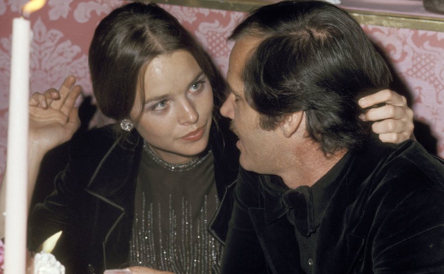 A dated picture of Michelle Phillips and Jack Nicholson sitting in a restaurant.