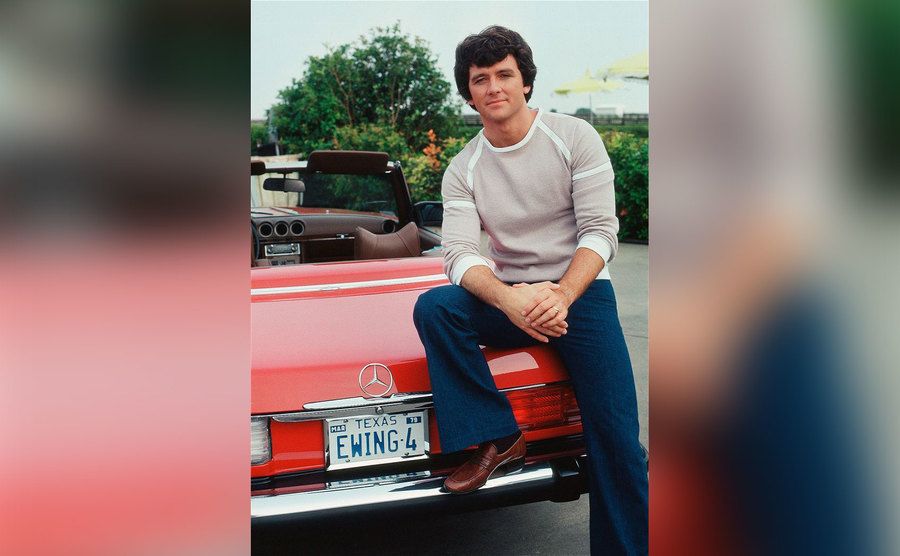 Patrick Duffy as Bobby Ewing sits on the trunk of his car. 