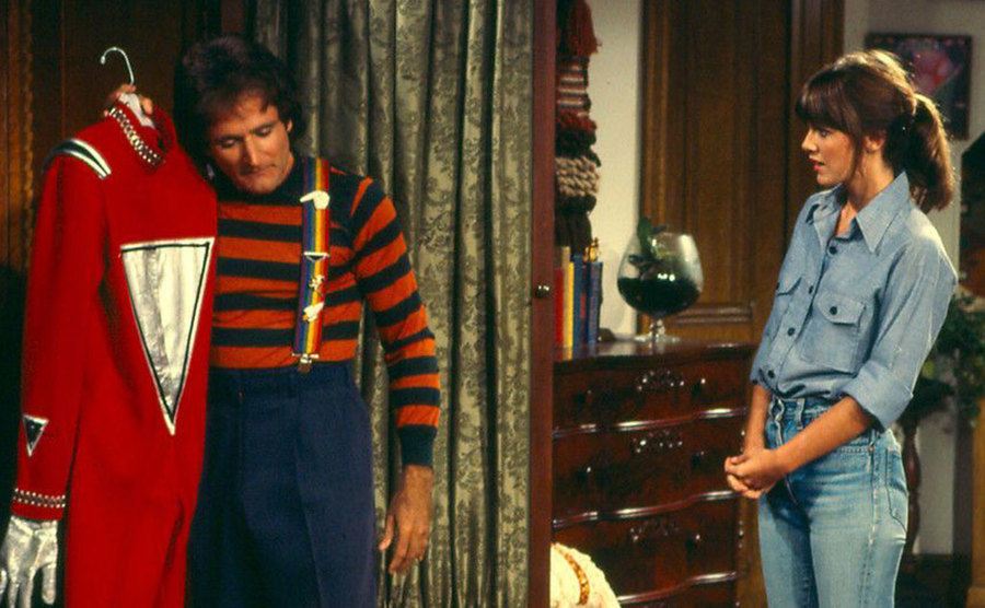 A still of Robin Williams holding the iconic red jumpsuit in a scene from the show.