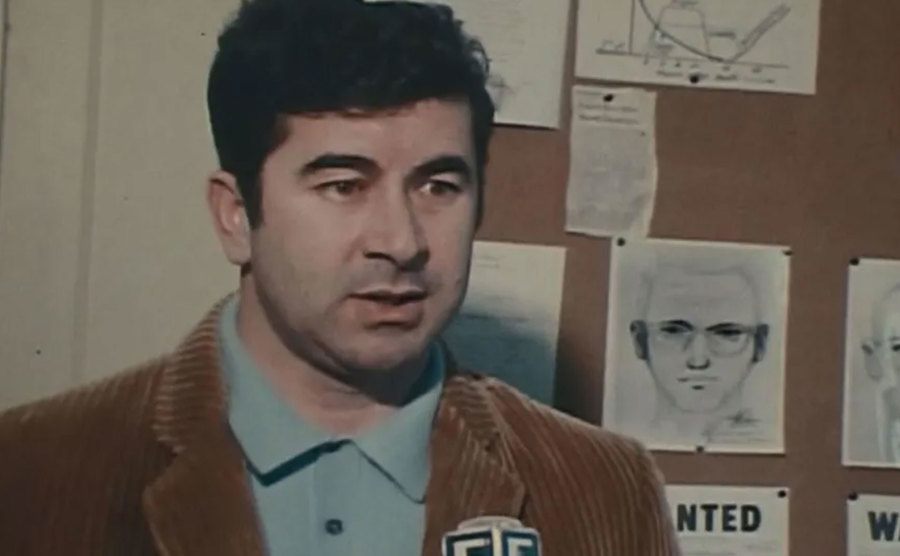 A dated video still of Toschi talking to the press.