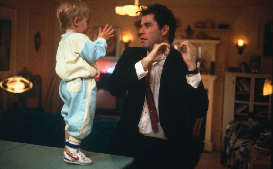 John Travolta and baby Mikey are dancing in a still from Look Who’s Talking. 