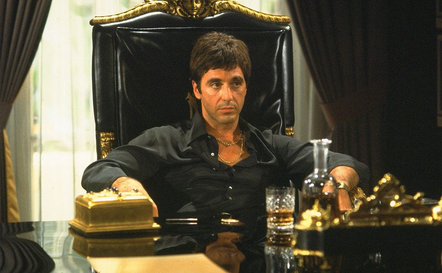 Al Pacino, as Tony Montana, sits in his home office. 