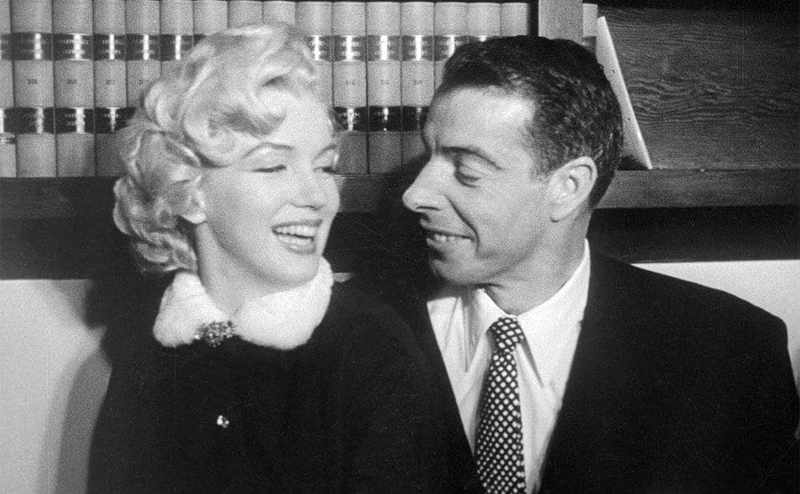 Marilyn Monroe and Joe DiMaggio share a laugh on the couch. 